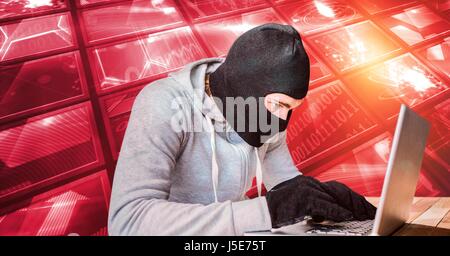 Digital composite of Hacker wearing monkey cap while using laptop Stock Photo
