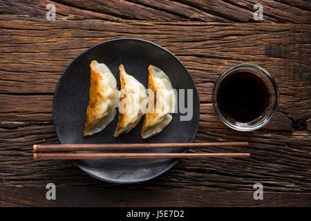 A plate of Japanese gyoza dumplings sitting on a rustic wooden table. Stock Photo