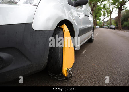 Impounded vehicle parked on street with vehicle immobiliser fitted (wheel clamp) by local authority, Merton, Southwest London, UK Stock Photo