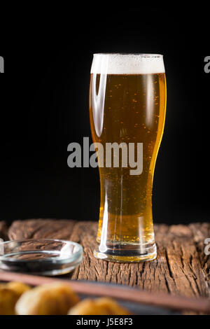 A pint of Craft Beer sitting on a rustic wooden bar. Handcrafted microbrewery ale. Stock Photo