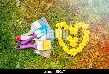 Green background with heart from flowers of a dandelion and multicolored tassels. The horizontal frame. Stock Photo