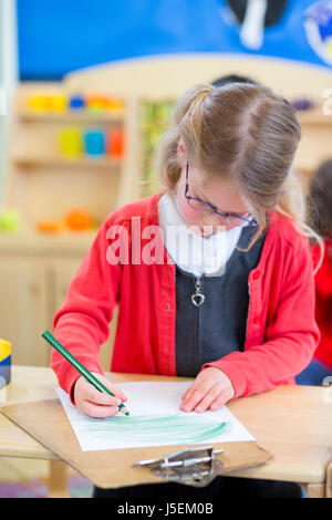 Little girl drawing a picture at nursery in the classroom. Stock Photo