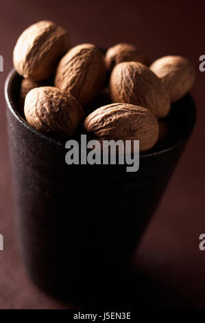 Nutmeg, Mace, Myristica fragrans, Mass of brown coloured spice in cup. Stock Photo