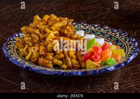 Chak-chak oriental sweets, dried fruit and figured sugar in a traditional oriental plate on an old cracked varnished surface Stock Photo