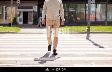 senior man walking along city crosswalk Stock Photo