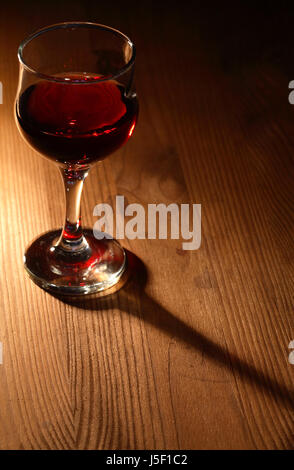 Elegant goblet of red wine with long shadow on wooden table Stock Photo