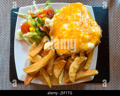 Chicken Parmesan or ”Parmo” a popular dish in North East England  deep-fried breaded chicken with béchamel sauce and melted cheese  chips and salad. Stock Photo