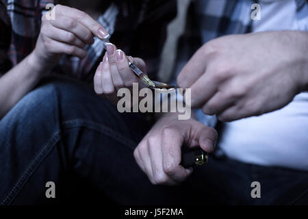 Young freaks heating drugs over the flame in the darkness Stock Photo