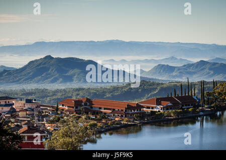 Stunning Sarangan lake in the mountains of east Java, beautiful scenery with morning mists caressing the mountains. A revealing high angle perspective Stock Photo