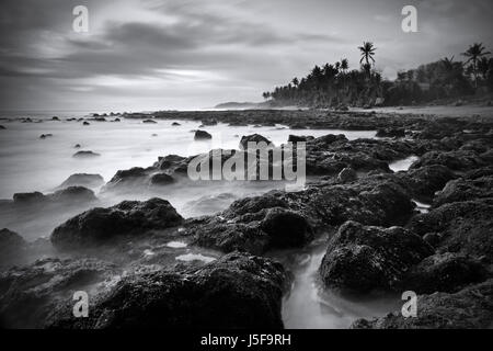 Beautiful black and white fine art picture of a Bali beach scene. Dramatic long exposure technique using monochrome to create atmosphere during sunset Stock Photo