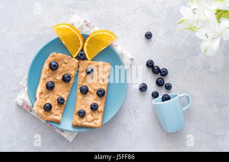 Breakfast for kids: peanut butter sandwich with fresh blueberries and orange shaped as butterfly. Top view Stock Photo