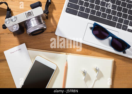 digital photography or planning photo vacation concept, showing items such as camera, computer, phone, and notebook on wooden table Stock Photo