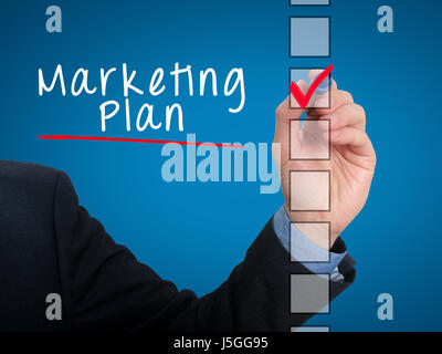 Businessman hand writing Marketing Plan and check listing task. Isolated on blue background. Stock photo Stock Photo