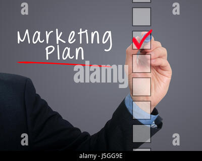 Businessman hand writing Marketing Plan and check listing task. Isolated on grey background. Stock photo Stock Photo