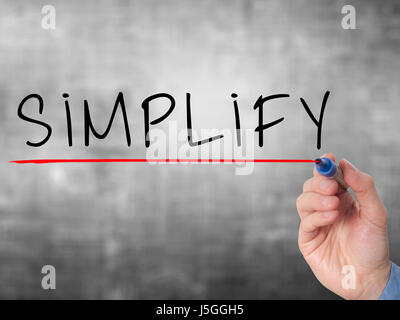 Businessman hand writing Simplify with marker on transparent wipe board isolated on grey. Stock Image Stock Photo