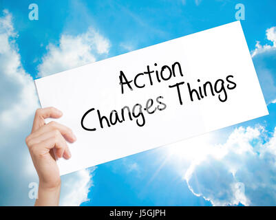 Action Changes Things Sign on white paper. Man Hand Holding Paper with text. Isolated on sky background.   Business concept. Stock Photo Stock Photo