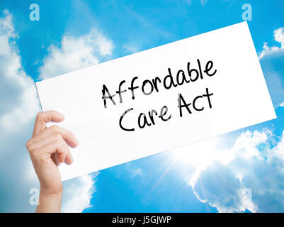 Affordable Care Act Sign on white paper. Man Hand Holding Paper with text. Isolated on sky background.  Business concept. Stock Photo Stock Photo