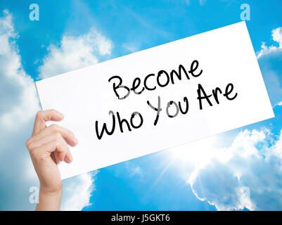 Become Who You Are Sign on white paper. Man Hand Holding Paper with text. Isolated on sky background.  Business concept. Stock Photo Stock Photo