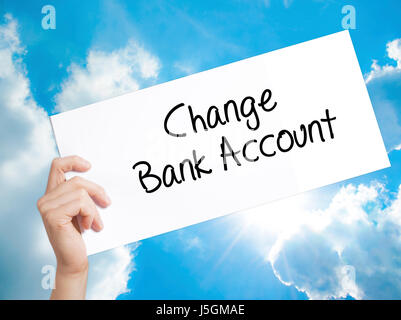Change Bank Account Sign on white paper. Man Hand Holding Paper with text. Isolated on sky background.  Business concept. Stock Photo Stock Photo