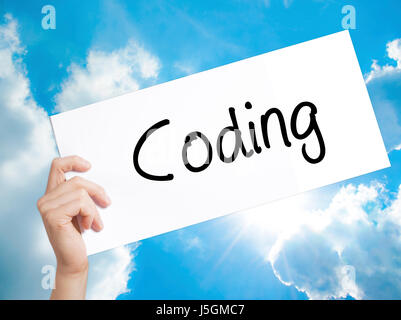 Coding Sign on white paper. Man Hand Holding Paper with text. Isolated on sky background.  Business concept. Stock Photo Stock Photo