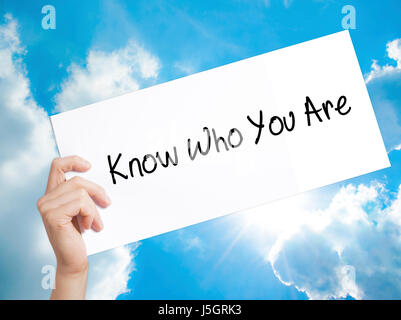 Know Who You Are Sign on white paper. Man Hand Holding Paper with text. Isolated on sky background.  technology, internet concept. Stock Photo