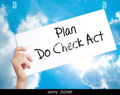 Plan Do Check Act  Sign on white paper. Man Hand Holding Paper with text. Isolated on sky background.   Business concept. Stock Photo Stock Photo