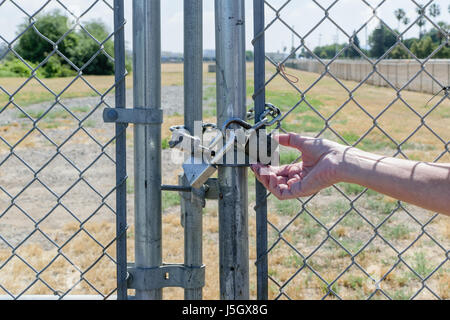 Women unlocks one of three locks on gate