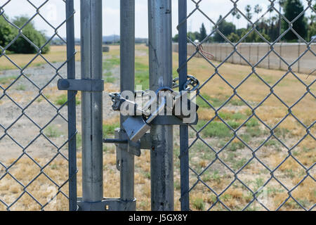 Three locks secure gate on fence Stock Photo