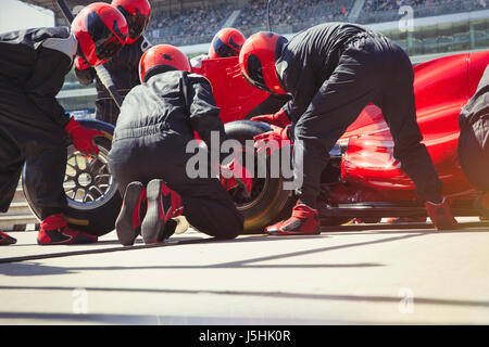 Pit crew replacing tires on formula one race car in pit lane Stock Photo