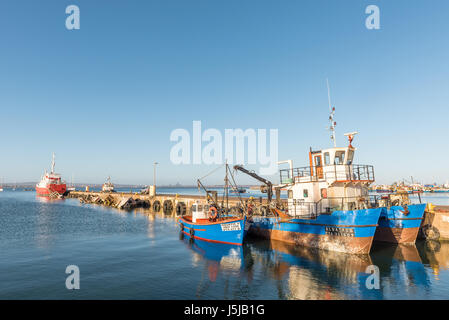 SALDANHA BAY, SOUTH AFRICA - APRIL 1, 2017: Several ships and a sunken ship at sunset at a pier in Saldanha Bay, a town in the Western Cape Province Stock Photo