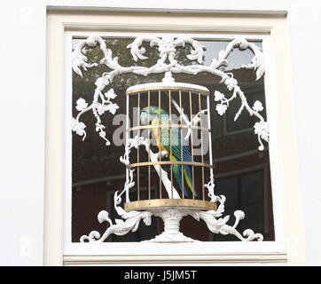 Ornamental wood carved Blue and Gold macaw in a cage, over a door in Bergstraat, city centre of Deventer, Netherlands. Stock Photo