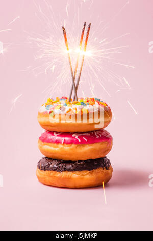Delicious donuts for birthday on pastel pink background. Stock Photo