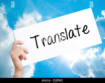 Translate Sign on white paper. Man Hand Holding Paper with text. Isolated on sky background.   Business concept. Stock Photo Stock Photo