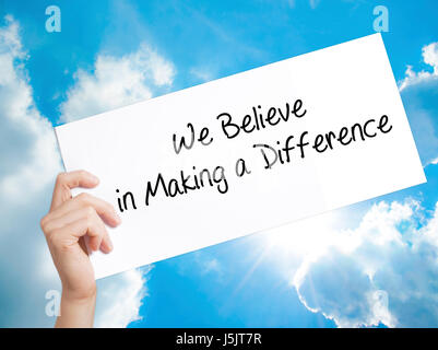 We Believe in Making a Difference Sign on white paper. Man Hand Holding Paper with text. Isolated on sky background.  Business concept. Stock Photo Stock Photo