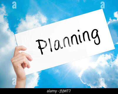 Planning Sign on white paper. Man Hand Holding Paper with text. Isolated on sky background.  Business concept. Stock Photo Stock Photo