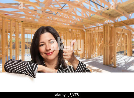 Hispanic Woman With Thumbs Up On Site Inside New Home Construction Framing. Stock Photo