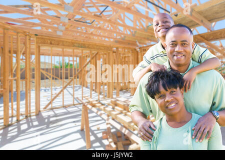 Young African American Family On Site Inside Their New Home Construction Framing. Stock Photo
