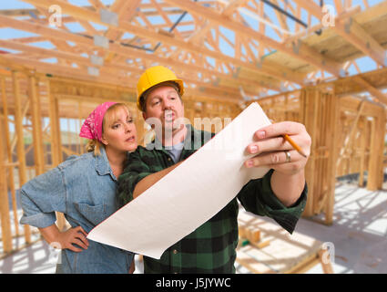 Contractor Showing Plans to Woman On Site Inside New Home Construction Framing. Stock Photo