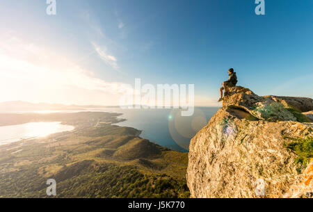 A traveler on the top of the mountain is enjoying the stunning view at sunset in Sardinia, Italy. Stock Photo
