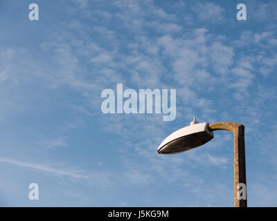 the top of a street light outside turned off during day with a blue and white sky broken not working and turned off spring day Stock Photo