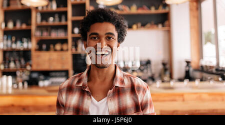 Portrait of happy young man laughing in a cafe. Young african male in a coffee shop having fun. Stock Photo