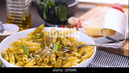 Close up revealing view of Italian pasta (penne) with pesto sauce Stock Photo