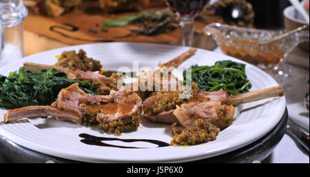 A rack of lamb in crusted mint sauce with spinach Stock Photo