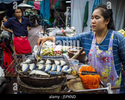 Bangkok, Bangkok, Thailand. 18th May, 2017. A woman grills fish on a street in Bangkok's Chinatown. City officials in Bangkok have taken steps to rein in street food vendors. The steps were originally reported as a ''ban'' on street food, but after an uproar in local and international news outlets, city officials said street food vendors wouldn't be banned but would be regulated, undergo health inspections and be restricted to certain hours on major streets. On Yaowarat Road, in the heart of Bangkok's touristy Chinatown, the city has closed some traffic lanes to facilitate the vendors. But in Stock Photo