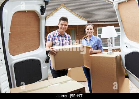 Young Couple Moving In To New Home  Unloading Removal Van Stock Photo