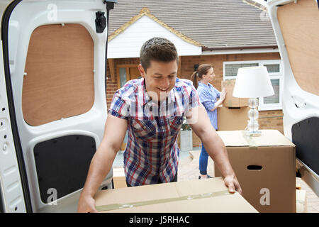 Young Couple Moving In To New Home  Unloading Removal Van Stock Photo