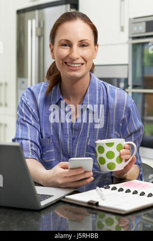 Portrait Of Female Freelance Worker Using Laptop In Kitchen At Home Stock Photo