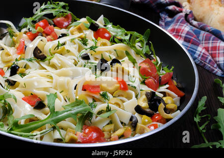 Pasta with crushed olives and cherry tomatoes, arugula. Horizontal shot. Stock Photo