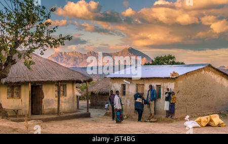 Traditional mud hut with grass roof alongside more modern hut with corrugated iron sheeting roof in a rural village in Malawi, Africa Stock Photo