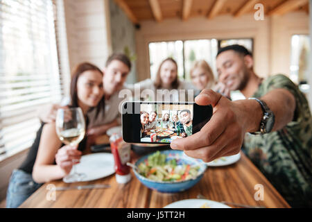 Group of friends having dinner and taking selfie with smartphone at the table Stock Photo